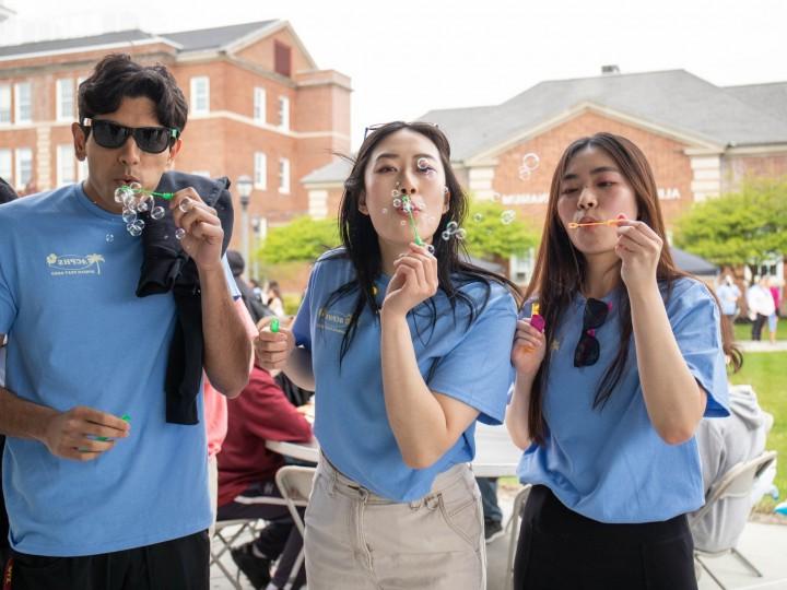 A group of students stand together and blow bubbles at Springfest